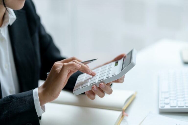 Close-up of businesswoman hands using a calculator to check company finances and earnings and budget